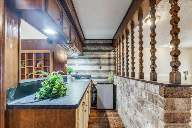 bar with wood walls, wet bar, a textured ceiling, and dark tile patterned flooring