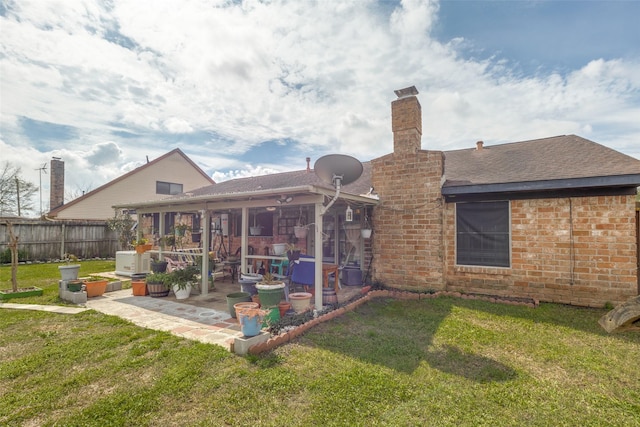 back of house with a patio, a lawn, a chimney, and fence