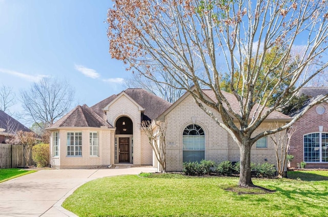 view of front of home featuring fence, a front lawn, concrete driveway, and brick siding