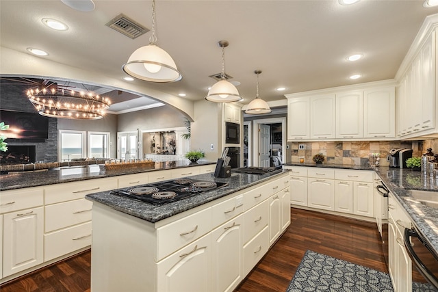 kitchen with black appliances, a kitchen island, visible vents, and dark wood-style floors