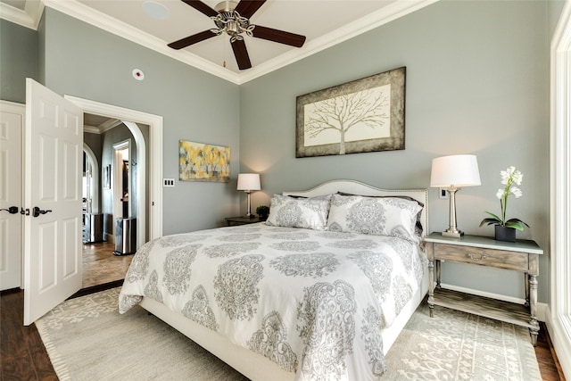 bedroom featuring baseboards, crown molding, arched walkways, and wood finished floors