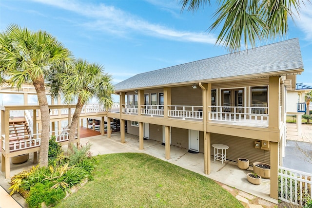 rear view of house featuring a shingled roof, a patio area, and a yard