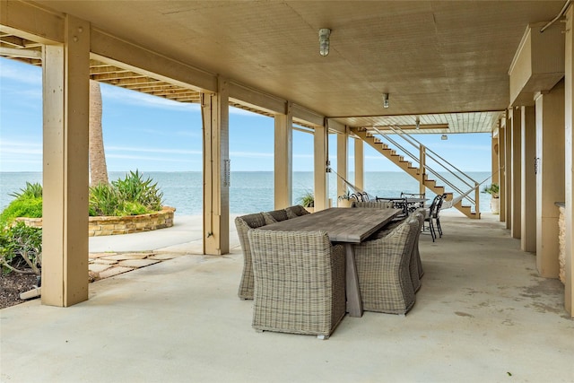 view of patio featuring a water view, stairway, and outdoor dining space