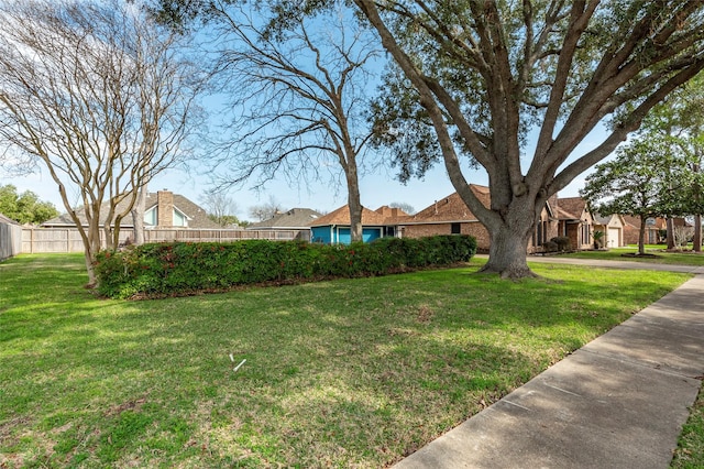 view of front of home featuring brick siding, fence, and a front yard