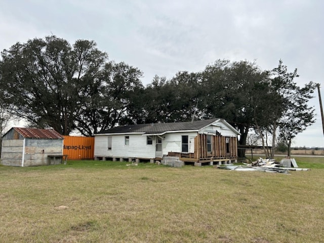 rear view of house featuring a lawn and an outdoor structure
