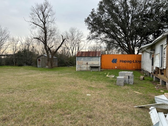 view of yard featuring fence, a storage unit, and an outbuilding