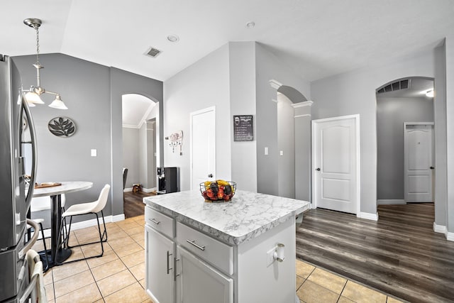 kitchen with light countertops, arched walkways, freestanding refrigerator, and visible vents