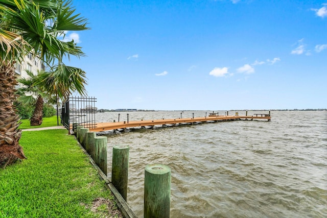 view of dock with a yard and a water view