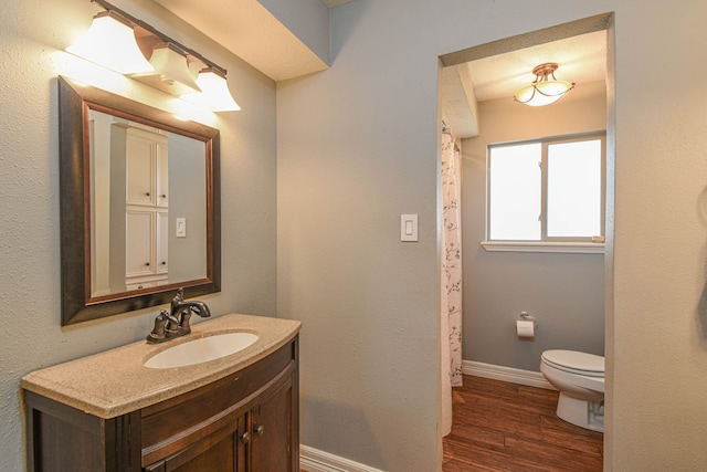 full bath with toilet, wood finished floors, vanity, baseboards, and a shower with curtain