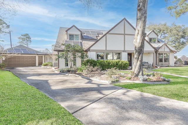 view of front of house with solar panels, brick siding, a shingled roof, concrete driveway, and a front yard