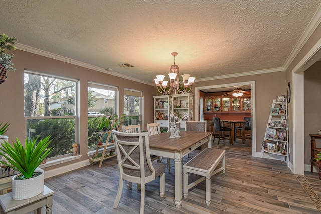 dining area with a textured ceiling, ornamental molding, ceiling fan with notable chandelier, and wood finished floors