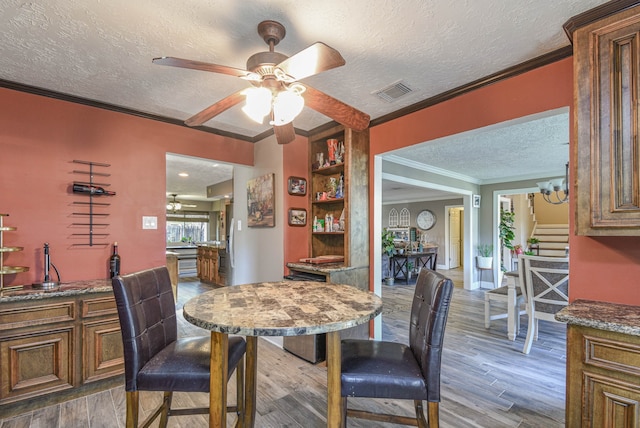 dining room featuring stairway, wood finished floors, visible vents, and crown molding