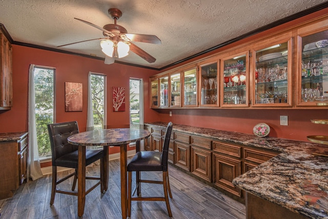 dining area featuring ornamental molding, dark wood-style flooring, and a textured ceiling