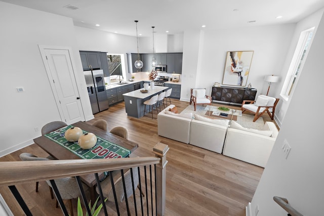 living room with light wood-style floors, baseboards, visible vents, and recessed lighting