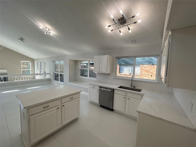 kitchen with tasteful backsplash, white cabinets, dishwasher, vaulted ceiling, and a sink