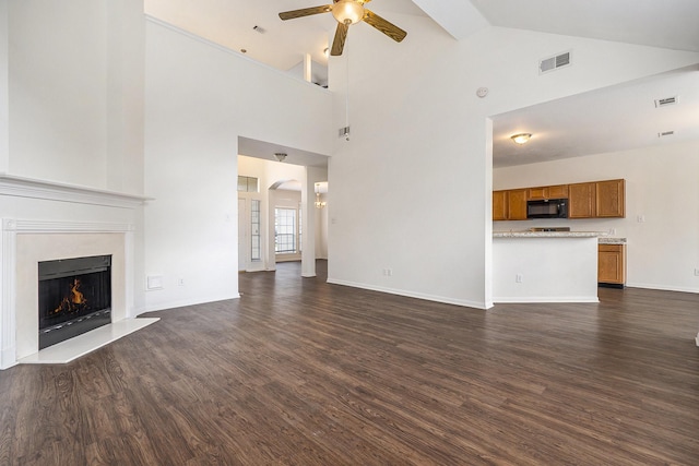 unfurnished living room featuring baseboards, visible vents, a premium fireplace, dark wood-style flooring, and ceiling fan