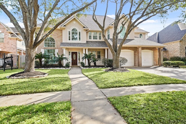 view of front facade featuring a garage, concrete driveway, fence, a front yard, and brick siding