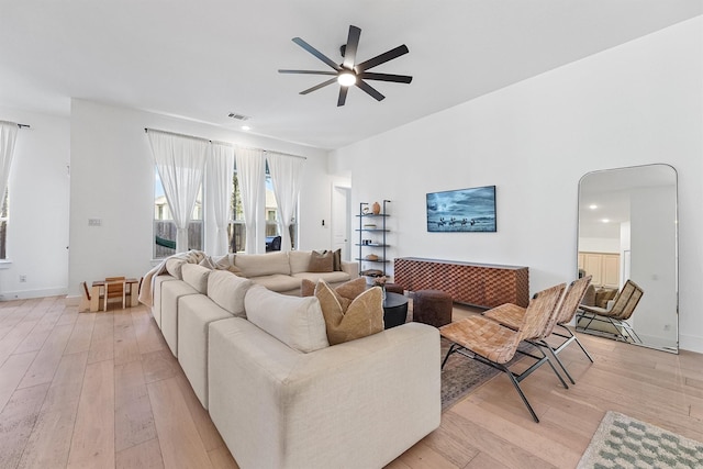 living room with light wood-style floors, visible vents, ceiling fan, and baseboards