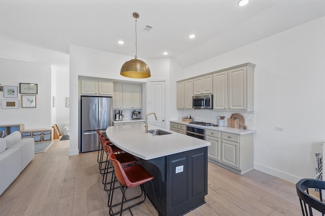 kitchen with a kitchen breakfast bar, a sink, light countertops, stainless steel appliances, and backsplash