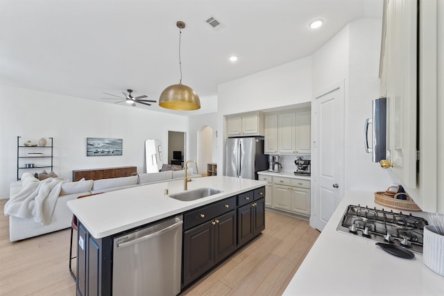 kitchen with arched walkways, stainless steel appliances, a sink, and light countertops