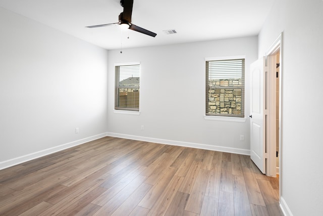 unfurnished room with a ceiling fan, visible vents, baseboards, and wood finished floors