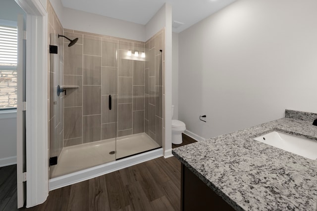 full bathroom with toilet, a stall shower, vanity, wood finished floors, and baseboards