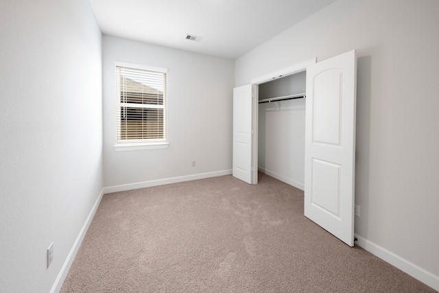 unfurnished bedroom with baseboards, a closet, visible vents, and light colored carpet