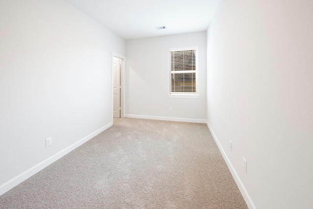 spare room with visible vents, baseboards, and light colored carpet