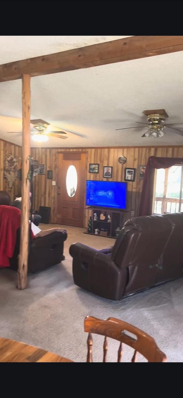 living room with ceiling fan, wooden walls, and carpet flooring