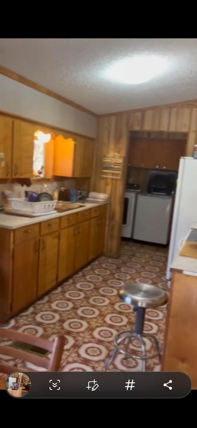 kitchen featuring washer / dryer, crown molding, brown cabinets, and light countertops