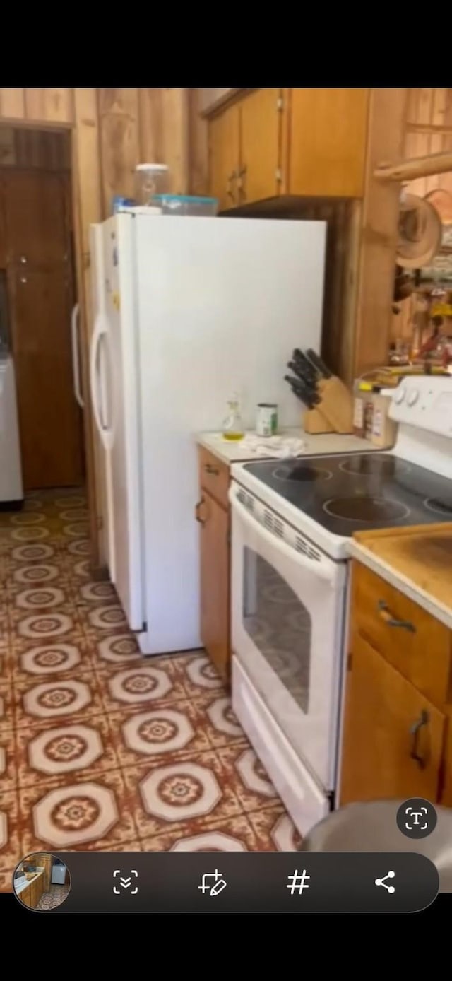 kitchen with electric stove, brown cabinetry, light countertops, and washer / dryer