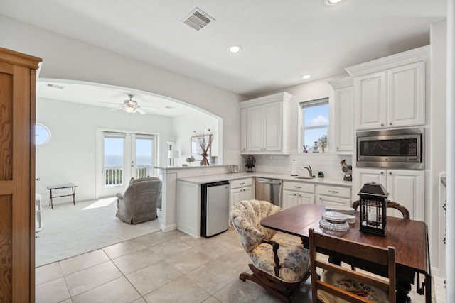 kitchen featuring arched walkways, stainless steel appliances, a sink, visible vents, and light countertops