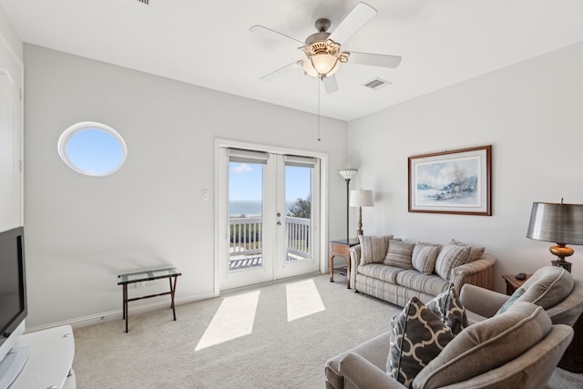 carpeted living area featuring ceiling fan, visible vents, baseboards, and french doors