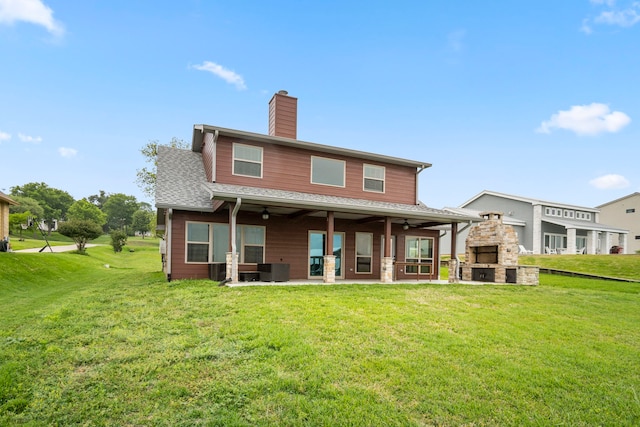 rear view of house with a yard, ceiling fan, a fireplace, and a patio