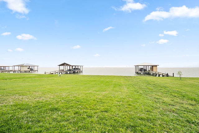 view of dock with a water view and a yard