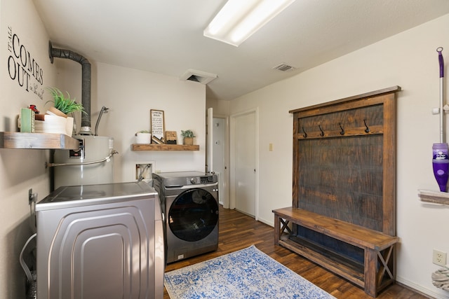 clothes washing area featuring laundry area, visible vents, dark wood-style flooring, independent washer and dryer, and water heater