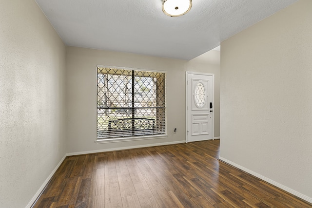 spare room with baseboards, a textured wall, a textured ceiling, and hardwood / wood-style floors