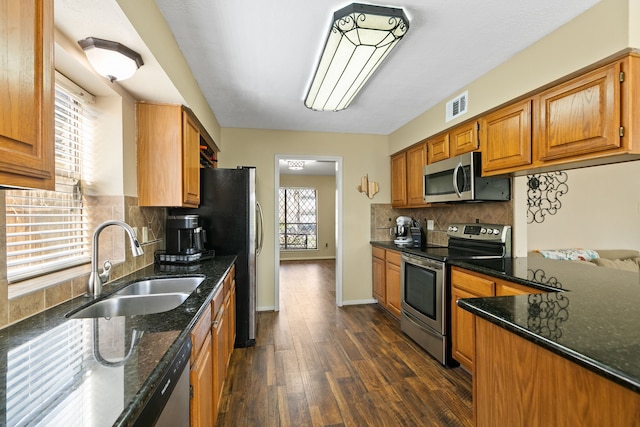 kitchen with visible vents, dark stone counters, dark wood-style floors, appliances with stainless steel finishes, and a sink