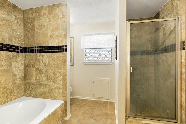 bathroom with a textured ceiling, a garden tub, toilet, baseboards, and a shower stall