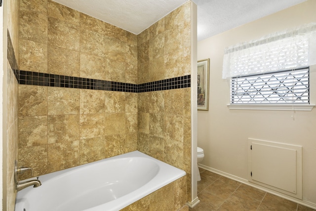 bathroom featuring tile patterned flooring, baseboards, a textured ceiling, and toilet