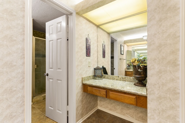 bathroom with a stall shower, tile patterned flooring, vanity, and a textured ceiling