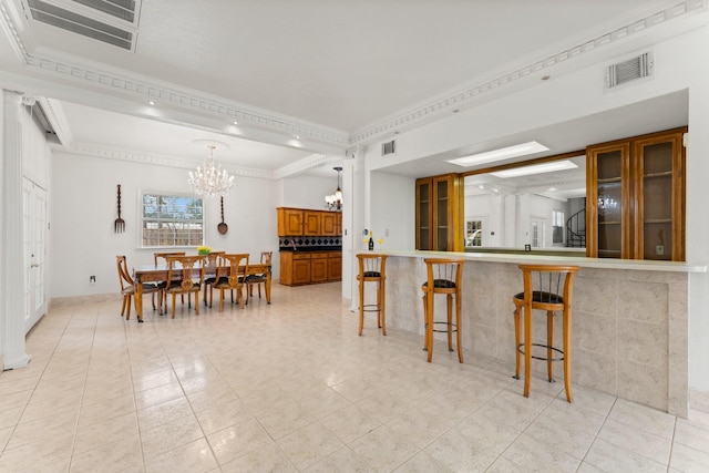 dining space with ornamental molding, visible vents, and an inviting chandelier