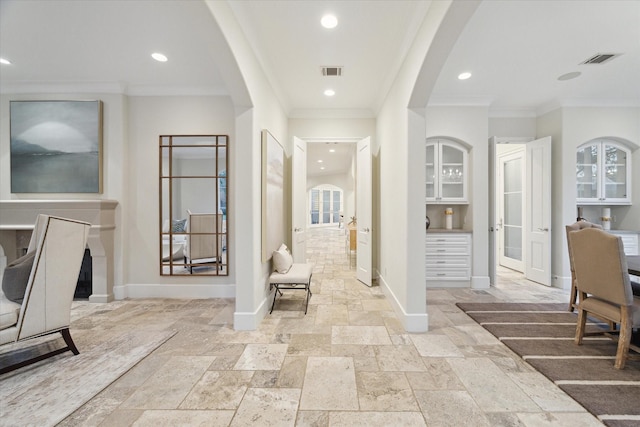 corridor with arched walkways, stone tile flooring, visible vents, and baseboards