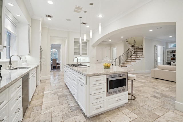 kitchen featuring stone tile floors, baseboards, appliances with stainless steel finishes, ornamental molding, and a sink