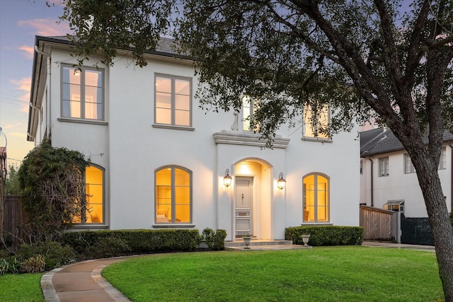 view of front facade with a yard, fence, and stucco siding