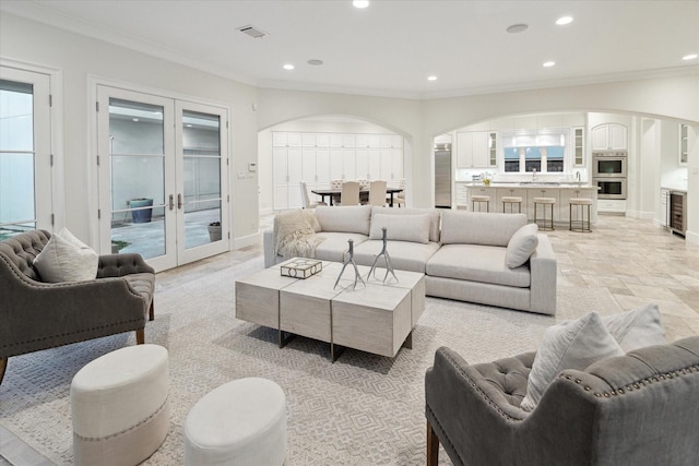 living area featuring recessed lighting, visible vents, arched walkways, and french doors