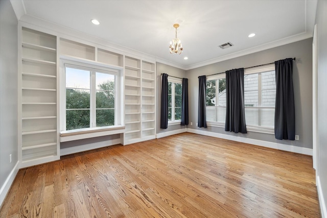 spare room with a notable chandelier, visible vents, baseboards, light wood-type flooring, and crown molding