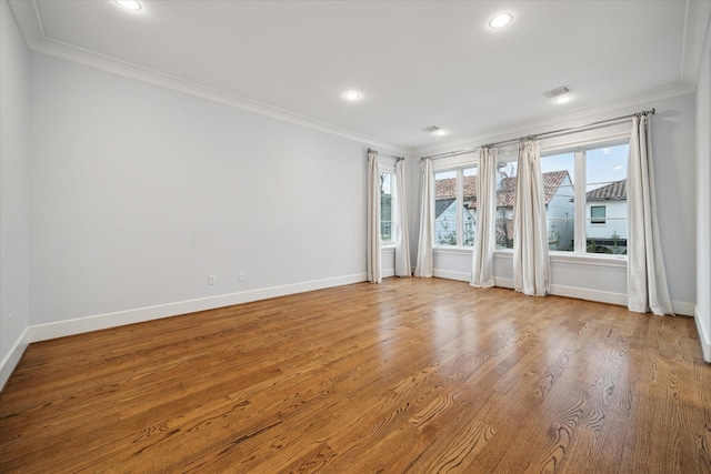 empty room featuring baseboards, visible vents, ornamental molding, wood finished floors, and recessed lighting