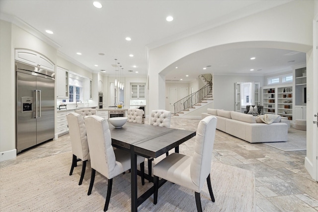 dining area featuring arched walkways, stone tile flooring, crown molding, and recessed lighting