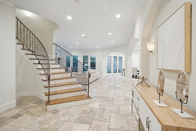 staircase featuring stone tile floors, arched walkways, and baseboards